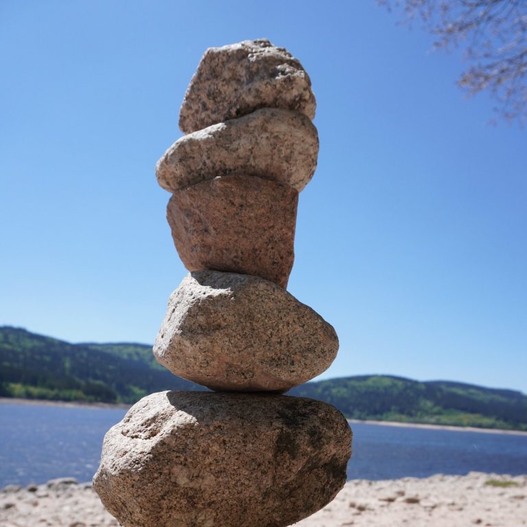 Schluchsee Strand Fünf Steine sind übereinander gestapelt, vor einem klaren Himmel und Wasser.